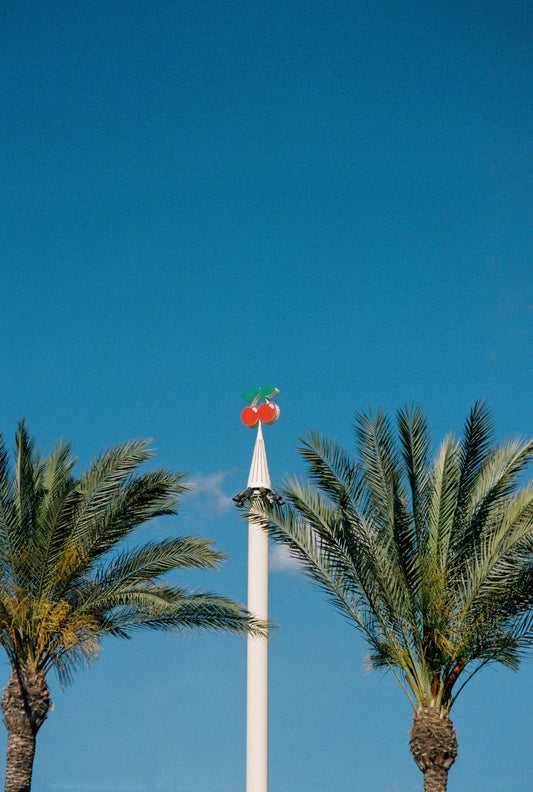 Fotografía analógica Cherries On Top en Ibiza por Sofía Gómez-Fonzo, logo de Pacha con cielo azul