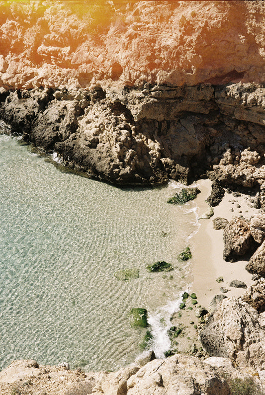 Fotografía analógica en Ibiza por Sofía Gómez-Fonzo, cala escondida con mar y arena dorada